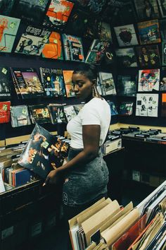 a woman is looking through records in a record store