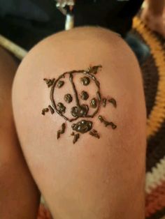 a ladybug tattoo on the back of a woman's thigh is shown