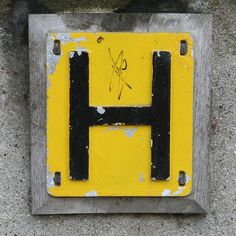 a yellow and black sign that has the letter h written in cursive writing