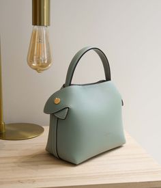 Elevate your style with our Mini Swann bag in Jade Green. Crafted from smooth calf leather, this little gem of craftsmanship perfectly complements a wide range of outfits, from the simplest to the most colorful. Its vibrant and refreshing Jade Green shade elegantly pairs with soft colors such as white, cream, or sand, offering a classic and bright style. For a bold touch, pair it with soft shades like powder pink for a refreshingly contrasting look. This bag also blends perfectly with monochrome outfits in shades of Jade Green, for sophisticated color harmony. Handmade in our Italian workshop, the Mini Swann in Jade Green stands out for its smooth leather and refined finishes. Versatile in its carry, it can be held by hand, over the shoulder, or crossbody thanks to its adjustable strap. I Pink Leather Bag, Bright Fashion, Color Harmony, Scarf Headband, Metal Accessories, Of Outfits, Powder Pink, Leather Care, Jade Green