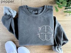 a gray sweatshirt with the words peace written on it next to shoes and plant pot