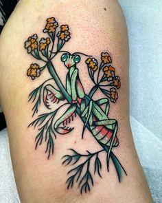 a tattoo on the leg of a woman with flowers and a praying mantissa