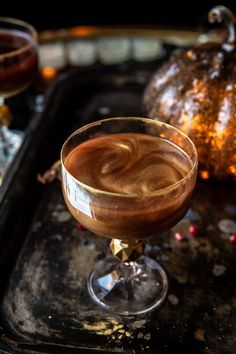 a glass filled with liquid sitting on top of a tray next to a pumpkin and other decorations