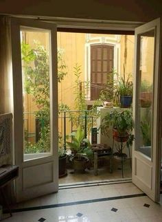 an open door leading to a patio with potted plants on the outside and inside