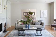 a living room filled with furniture and flowers on top of a coffee table in front of a fire place