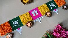 an arrangement of flowers, candles and decorations on a table with wall hangings in the background