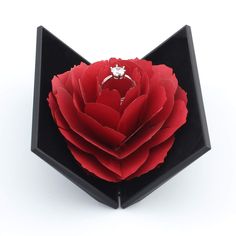 an origami rose in a black box on a white background with the lid open