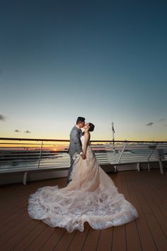 a bride and groom kissing on the deck of a cruise ship at sunset or dawn