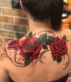 a woman's back tattoo with red roses on it