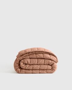 a pink quilted blanket on a white background with the top half folded up to show it's folds