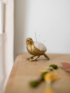 a gold bird sitting on top of a wooden table