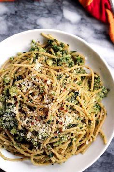 a white bowl filled with pasta and broccoli on top of a marble counter