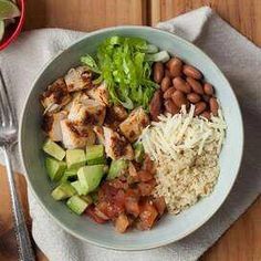 a white bowl filled with meat, beans and veggies next to a fork