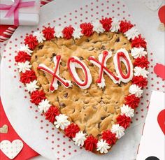 a heart - shaped cookie cake with the word xoxo spelled in red and white icing