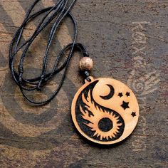 a wooden necklace with a yin symbol on it sitting on a piece of wood next to a string