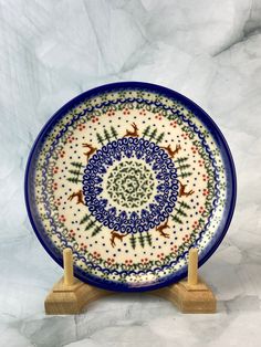 a blue and white plate with deer designs on the front is sitting on a wooden stand