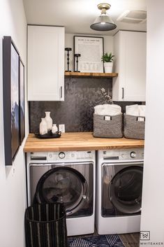 a washer and dryer in a small room with white cabinets on the wall