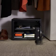 an open safe sitting on top of a carpeted floor next to a pair of shoes