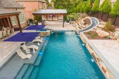 an outdoor swimming pool with lounge chairs and umbrellas next to the side of it