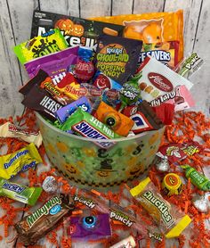 a basket filled with candy and candies on top of a bed of orange shredded paper