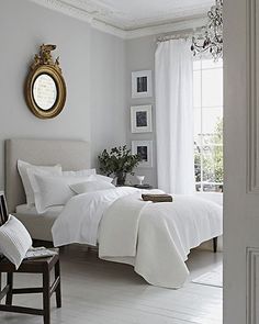 a white bedroom with two beds and a chandelier