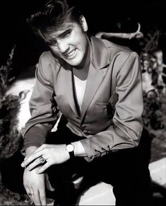 black and white photograph of a young man in a suit with his hand on the ground