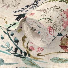 a floral wallpaper with white and pink flowers on it's side, next to a rolled up roll of paper