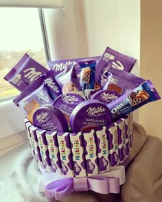 a basket filled with chocolates and candy bars on top of a table next to a window