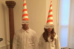 two people wearing orange and white hats standing next to each other in a living room