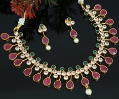 This stunning gold-plated necklace features an array of dazzling American diamonds, rubies and emeralds. Perfect for parties or special occasions, this eye-catching piece will add a touch of luxury to any look. Ruby Emerald Necklace Indian, Emerald Necklace Indian, Ruby Emerald Necklace, Diamond Necklace Gift, Ruby Set, Necklace Indian, Ruby Emerald, Indian Wedding Jewelry, Kundan Necklaces