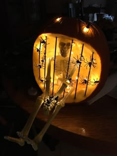 a skeleton sitting in front of a lighted pumpkin