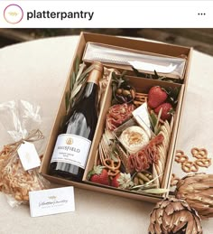 a wine bottle and some food in a box on a table next to an ornament