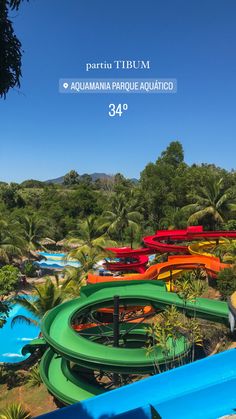 there are many colorful water slides in the park with trees and blue sky behind them