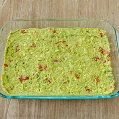 a glass casserole dish filled with guacamole on a wooden table