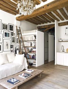 a living room filled with white furniture and pictures on the wall above it's coffee table