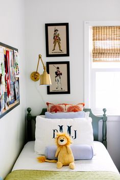 a bed with a teddy bear sitting on top of it next to two framed pictures