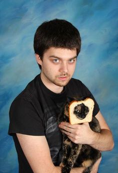 a young man holding a piece of bread in his right hand and looking at the camera