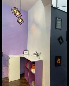 a purple and white room with some lights hanging from it's ceiling above the counter