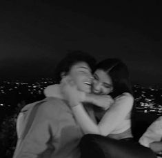 black and white photograph of two people hugging each other in front of the city lights