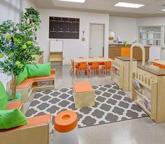 a classroom with orange and green chairs, desks, bookshelves and chalkboard