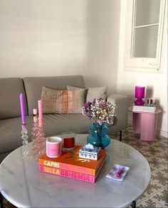 a living room filled with furniture and flowers on top of a coffee table in front of a gray couch