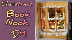 an open book with christmas decorations on the window and candles in the box next to it