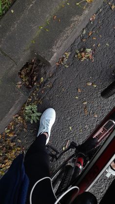 a person standing next to a bike on the street with their feet propped up in front of them