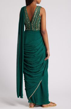 This saree has a hand-embroidered cropped top with intricate beadwork and lustrous sequins and is paired with a skirt featuring attached wraparound draping. This outfit is prestitched, so you can put it together in 30 seconds or less. V-neck Top has hook-and-eye closure; skirt has hidden side-zip closure Top and skirt feature hook-and-eye attachments for easy drape adjustments Lined 100% viscose Spot clean Made in India Asian & Pacific Islander Owned/Founded Festive Silk Pre-draped Saree With Sequins, Embellished Georgette Pre-draped Saree, Traditional Embellished Pre-draped Saree For Festive Season, Designer Sequin Dresses With Traditional Drape, Embellished Art Silk Blouse Piece With Traditional Drape, Traditional Drape Sequin Dresses For Designer Wear, Embellished Draped Bollywood Lehenga, Bollywood Embellished Draped Lehenga, Bollywood Style Draped Embellished Lehenga