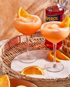 two glasses filled with orange juice and garnished with sugar, sit on a wicker tray