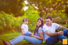 a man, woman and child are sitting in the grass