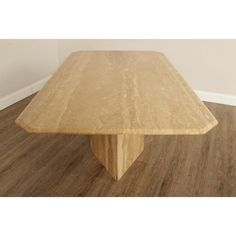 a large wooden table sitting on top of a hard wood floored floor next to a white wall