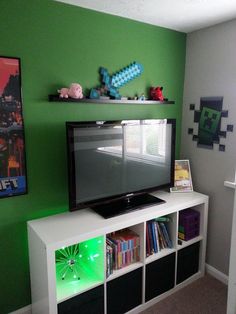 a flat screen tv sitting on top of a white entertainment center next to a green wall