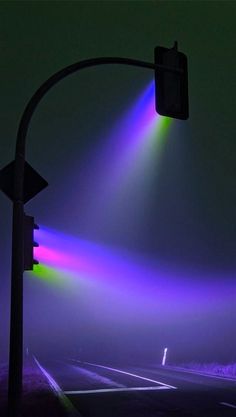 a traffic light on the side of a road at night with colored lights coming from it