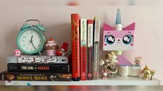 a shelf with books, toys and an alarm clock on top of each bookcase